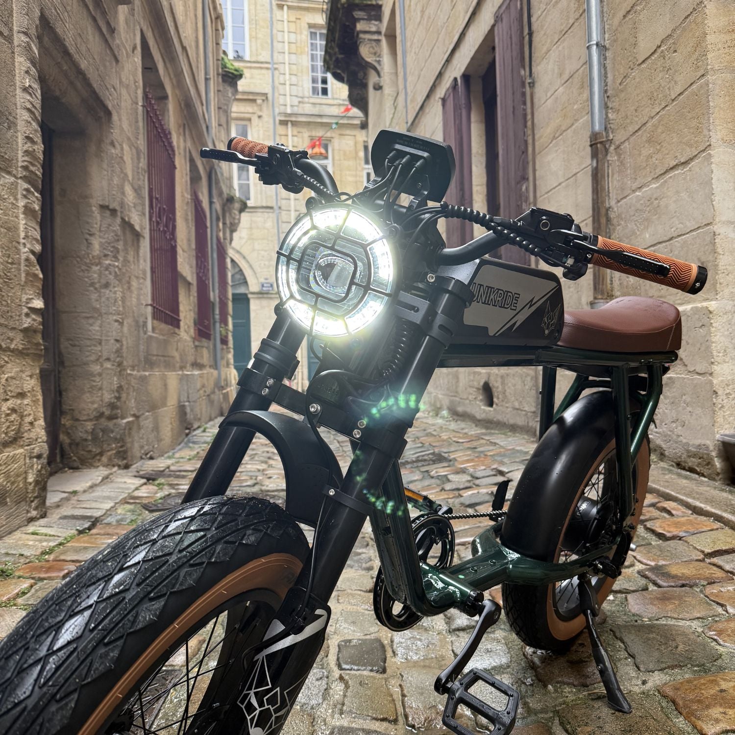 Fatbike électrique 2 places City S avec phare LED allumé dans une rue pavée, vélo électrique biplace urbain.