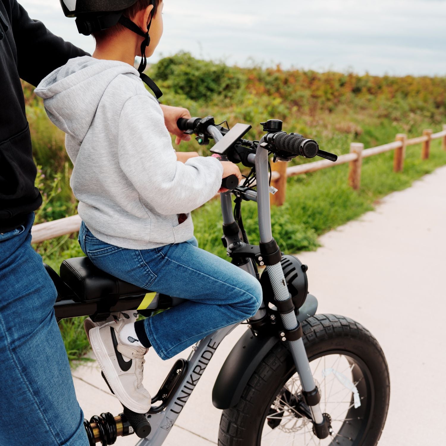Enfant assis sur un kit selle de cadre pour enfant monté sur vélo électrique UNIKRIDE